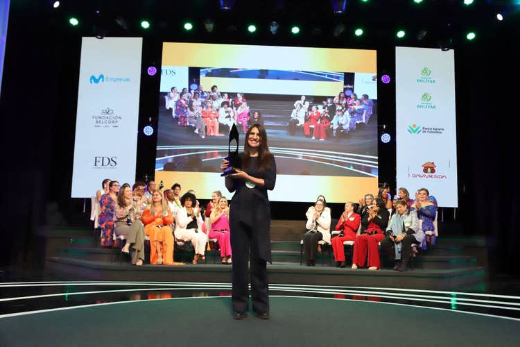 Sostiene el galardón Maria Paula Avila Osorio, Mujer Cafam 2023. La acompañan las 25 mujeres participantes de esta edición, y celebran su premiación.